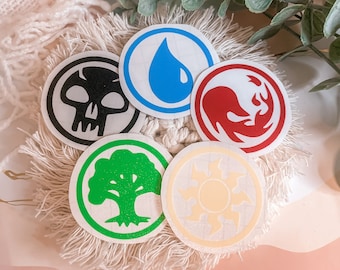 May include: Five round stickers with different symbols. The stickers are white with a black skull, a blue water drop, a red flame, a green tree, and a yellow sun.