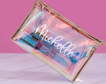 May include: A clear iridescent makeup bag with a gold zipper and the name "Michelle" printed in white on the front.