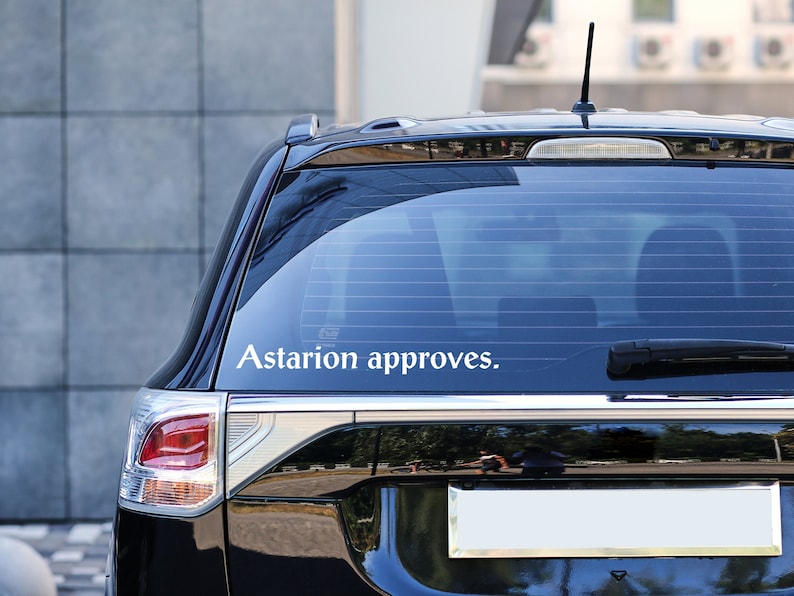 May include: A black SUV with a white sticker on the back window that says "Astarion approves."