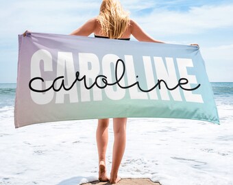 Puede incluir: Una persona sosteniendo una toalla de playa con un degradado de colores rosa, morado, azul y verde. La palabra "CAROLINE" está impresa en letras blancas con un contorno negro. La palabra "caroline" está escrita en cursiva en letras negras.