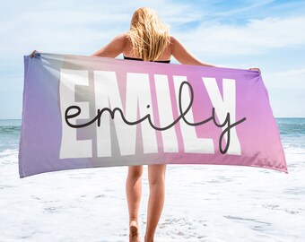 Puede incluir: Una toalla de playa con un degradado de colores rosa, morado y azul. La palabra "emily" está escrita en negro y blanco en la toalla.