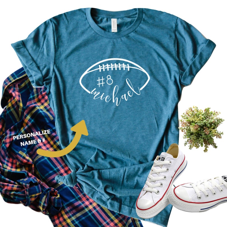 May include: A teal blue t-shirt with a white football graphic and the text '#8 michael'.