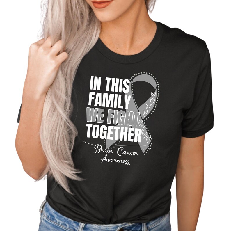 K&ouml;nnte beinhalten: Schwarzes T-Shirt mit einem wei&szlig;en Band und dem Text "In dieser Familie k&auml;mpfen wir zusammen" und "Bewusstsein f&uuml;r Hirntumor".