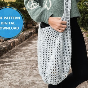 Könnte beinhalten: Eine hellblaue Häkel-Tragetasche mit einem breiten Riemen. Die Tasche wird von einer Person getragen, die einen grünen Pullover und eine schwarze Hose trägt. Der Text "PDF PATTERN DIGITAL DOWNLOAD" befindet sich in einem blauen Kreis.