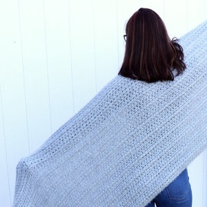 May include: A light blue fuzzy knit blanket draped over a person's shoulders.