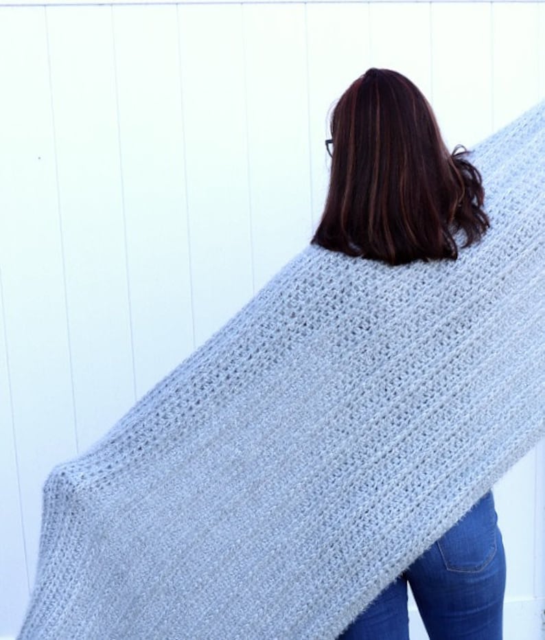 May include: A light blue fuzzy knit blanket draped over a person's shoulders.