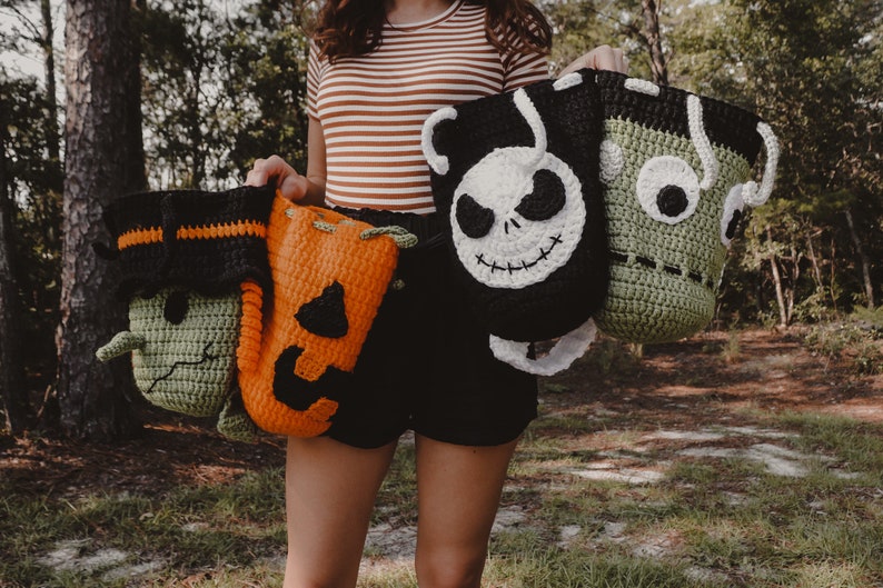 May include: Four crocheted Halloween trick-or-treat bags. One is green with a stitched-on monster face, one is orange with a stitched-on pumpkin face, one is black with a stitched-on Jack Skellington face, and one is green with a stitched-on Frankenstein face.