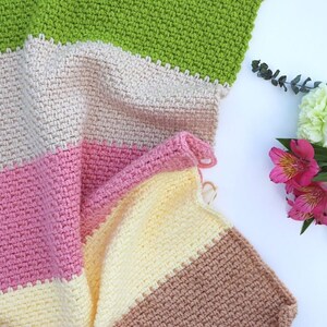 May include: A multi-colored crocheted blanket with stripes of green, beige, pink, yellow, and brown.