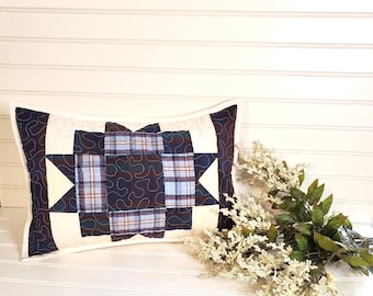 May include: A rectangular pillow with a white background and a blue and black plaid pattern in the center. The pillow is quilted with a swirl design.