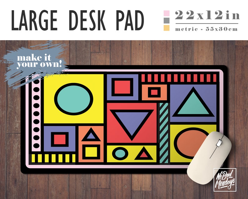 May include: A large desk pad with a geometric design featuring circles, squares, and triangles in various colors, including yellow, red, blue, green, and orange. The pad is 22 inches by 12 inches and has the text "make it your own!" in a gray box on the top left corner.
