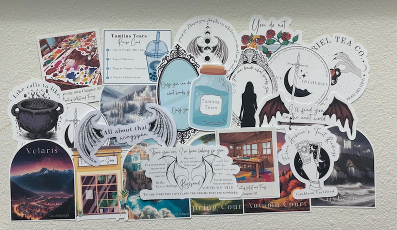 May include: A collection of colorful stickers featuring various designs, including wings, a cauldron, a bottle, a teacup, and a sword. The stickers are printed with text, such as "Tamlins Tears", "Velaris", "All about that wingspan", and "You do not".