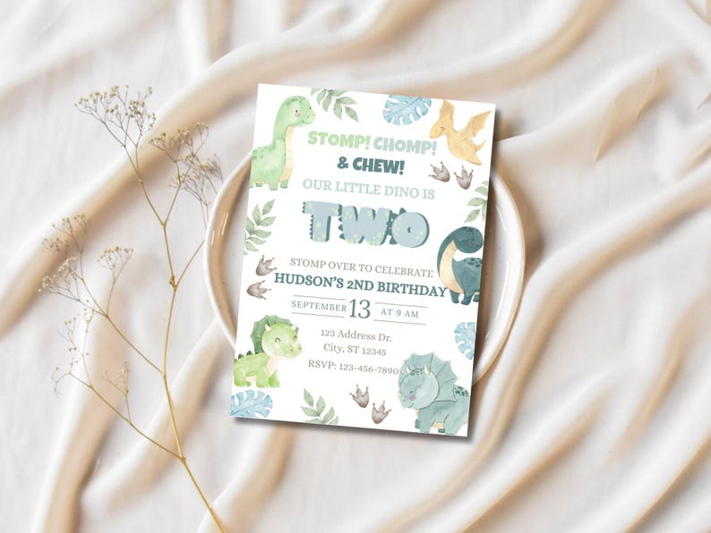 May include: A birthday invitation with a dinosaur theme. The invitation features watercolor illustrations of dinosaurs, leaves, and footprints. Text includes "STOMP! CHOMP! & CHEW! OUR LITTLE DINO IS TWO" and event details. The invitation is on a white plate.