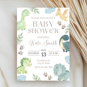 Può includere: Invito per baby shower con illustrazioni di dinosauri verdi, blu e gialli. Il testo recita "PLEASE JOIN US FOR A BABY SHOWER HONORING Kate Smith" con i dettagli dell'evento. Il design include elementi fogliari.