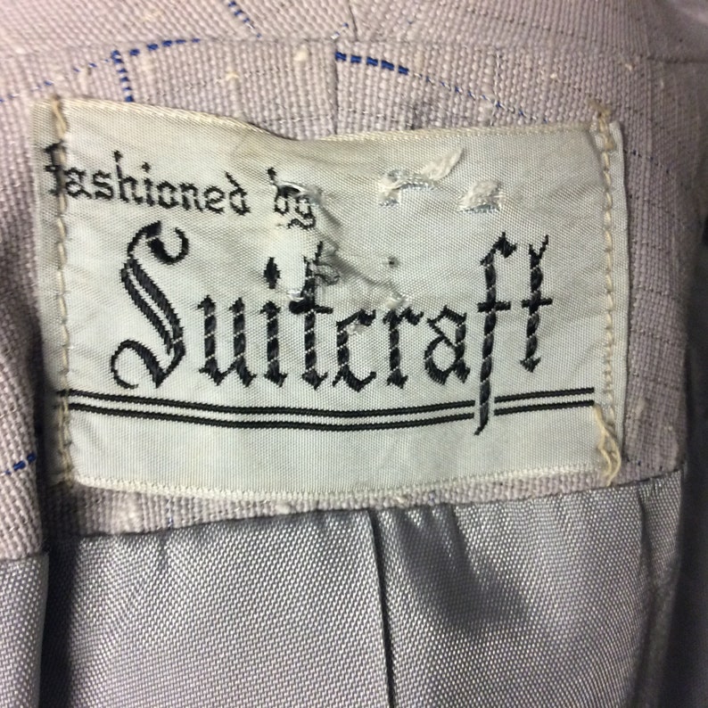 May include: A white label with black text that reads "fashioned by Suitcraft".