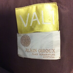 May include: A yellow label with the word "VALI" in white lettering, and a white label with the text "ALAIN GIROUX PLACE BONAVENTURE MONTREAL" in brown lettering.