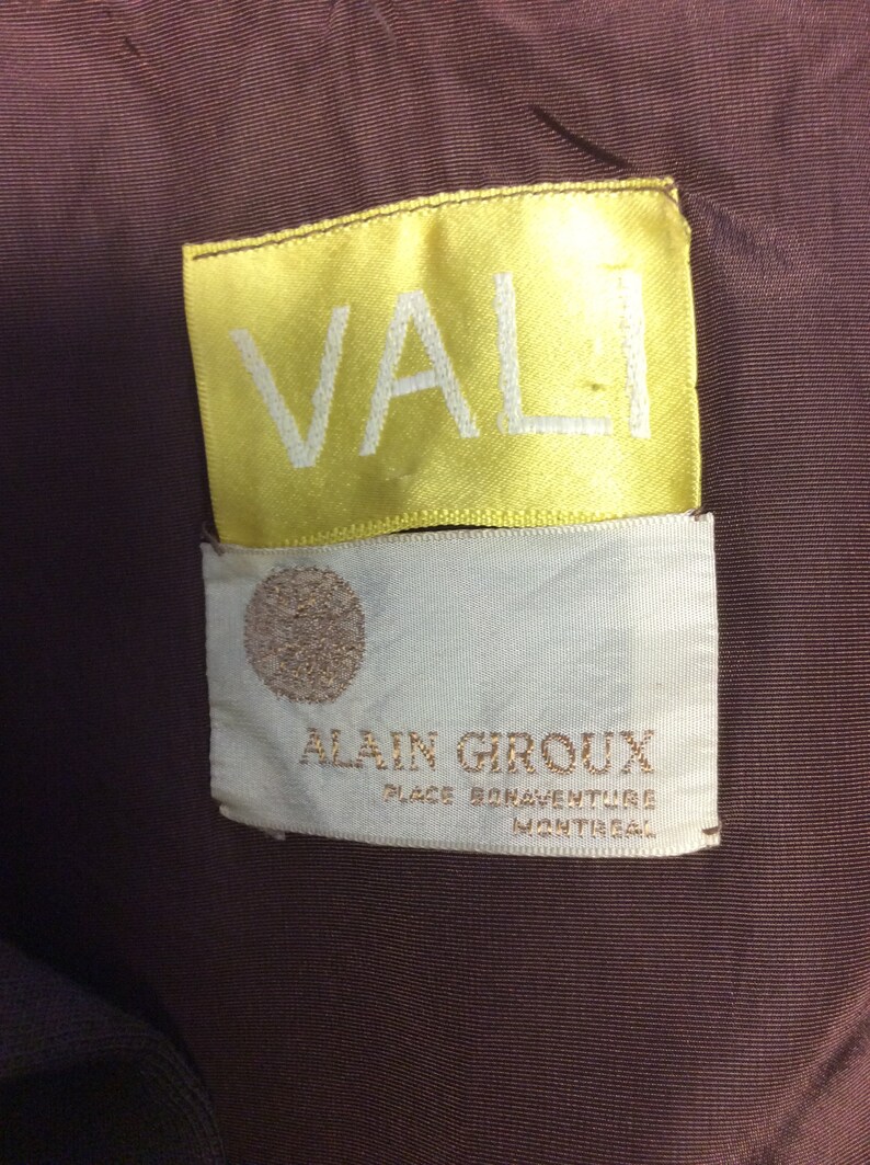May include: A yellow label with the word "VALI" in white lettering, and a white label with the text "ALAIN GIROUX PLACE BONAVENTURE MONTREAL" in brown lettering.