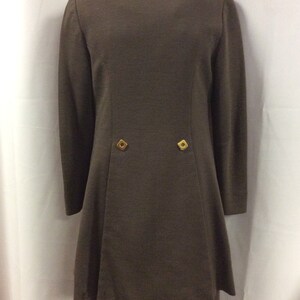 May include: A brown long-sleeved jacket with a white collar and two gold buttons on the back. The jacket is paired with matching brown pants.