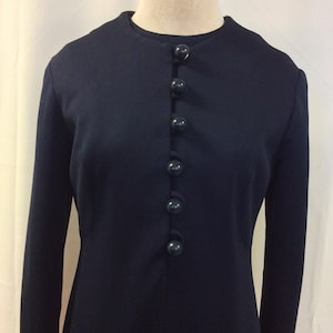 May include: A navy blue dress with a round neckline and a row of dark blue buttons down the front.