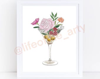 Puede incluir: Impresión artística en acuarela de una copa de Martini llena de aceitunas y flores. La copa contiene aceitunas verdes y está rematada con una rosa rosa, flores rojas y naranjas y hojas verdes. La obra de arte está enmarcada en un borde blanco.