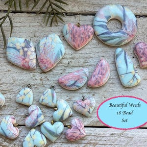 May include: A set of 18 polymer clay beads featuring a floral design with pink and blue colors. The beads are shaped as hearts, circles, and half-circles. The text "Beautiful Weeds 18 Bead Set" is visible in the image.