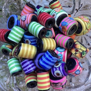 以下が含まれることがあります： カラフルなストライプと模様のポリマークレイビーズのコレクション。ビーズはすべて円筒形で、中央に穴が開いています。ジュエリーやその他のクラフトを作るのに最適です。
