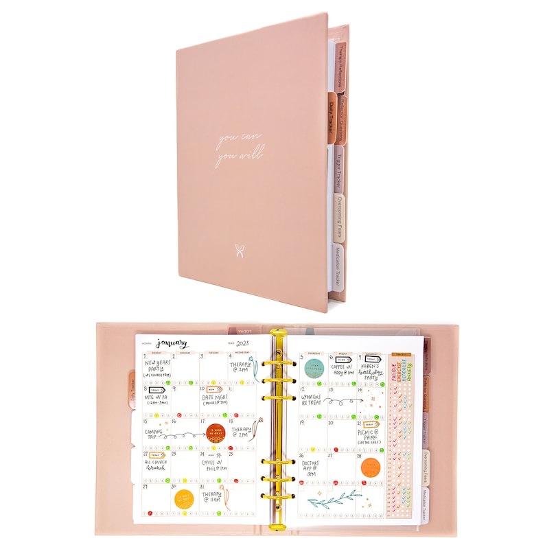 Peut inclure: Un agenda rose poudr&eacute; avec des anneaux dor&eacute;s et une inscription blanche qui dit "you can you will". L'agenda comporte des onglets pour diff&eacute;rentes sections, notamment "Planification de la th&eacute;rapie", "Suivi quotidien", "Suivi des d&eacute;clencheurs", "Surmonter les peurs" et "Suivi des habitudes". L'agenda est ouvert sur une vue mensuelle du calendrier pour janvier 2025.