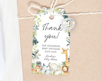 May include: Thank you tag featuring a jungle animal theme. The tag is white with black text that reads "Thank you!" and "For showering Baby Smithson with love. Ainsley's baby shower". The tag is surrounded by a green leafy border with a giraffe, zebra, elephant, lion, and monkey.