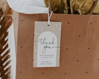 May include: A brown paper gift bag with white tissue paper lining and a gold gift tag. The tag says "Thank you" and "For showering us with love. Brianna's Baby Shower."
