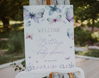 May include: A white welcome sign with a purple butterfly design. The sign reads "Welcome to Brittany's Baby Shower 18th August 2020".