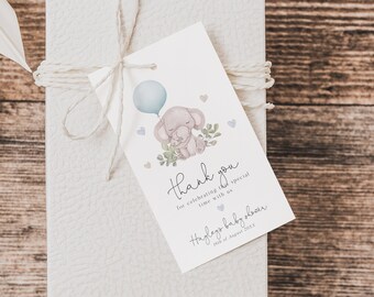 May include: A white gift box with a blue and gray elephant baby shower thank you tag. The tag features a cartoon elephant holding a blue balloon and the text "Thank you for celebrating this special time with us" and "Hodges Baby Shower 22nd of August 2023".