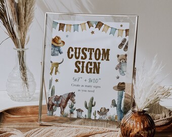 May include: A printable sign with a rustic western theme. The sign says "CUSTOM SIGN" and includes the text "5x7" + 8x10" Create as many signs as you need". The sign is decorated with cacti, stars, and cowboy hats.