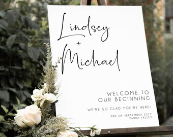 May include: White wedding sign with black calligraphy text that reads "Lindsey + Michael" and "Welcome to our beginning. We're so glad you're here! 3rd of September 2019, Yarra Valley".