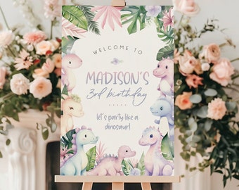 Puede incluir: Un cartel de bienvenida al 3er cumpleaños de Madison con temática tropical. El cartel presenta un dinosaurio rosa, morado y azul con hojas y flores verdes. El texto dice "Bienvenido al 3er cumpleaños de Madison... ¡Vamos a festejar como un dinosaurio!"