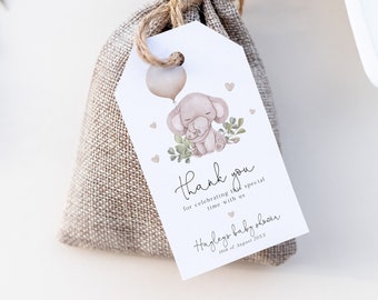 May include: A small burlap bag with a white tag attached. The tag features a watercolor illustration of a pink elephant holding a pink balloon and a smaller elephant. The tag also includes the text "Thank you for celebrating this special time with us.  Haylee's baby shower 18th of August 2023."