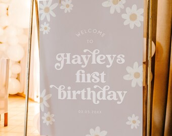 Op de afbeelding: Een welkomstbord voor een eerste verjaardag met een lichtpaarse achtergrond en witte madeliefjes. Het bord zegt "Welkom bij Hayleys eerste verjaardag 03.05.20XX".