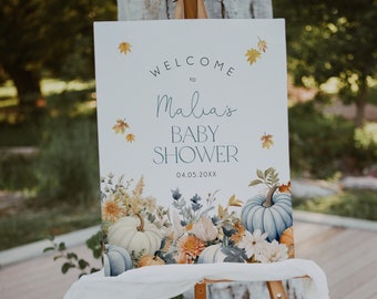 May include: Welcome to Malia's Baby Shower sign with a fall theme. The sign features a white background with blue and yellow floral accents and pumpkins. The text on the sign reads "Welcome to Malia's Baby Shower 04.05.20XX".