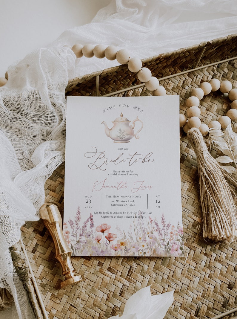 May include: A white bridal shower invitation with a watercolor floral border. The invitation features a teapot illustration and the text "Time for Tea with the Bride-to-be". The invitation also includes the bride-to-be's name, the date, time, and location of the shower.