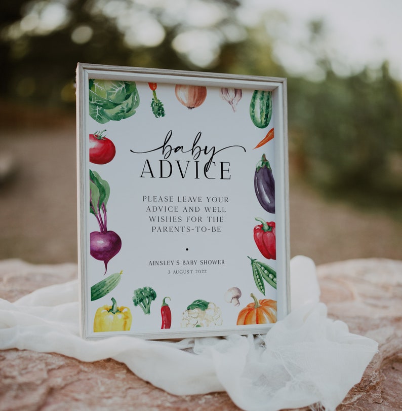 May include: A white sign with a watercolor illustration of vegetables and the text "baby ADVICE" in black script. The sign also includes the text "PLEASE LEAVE YOUR ADVICE AND WELL WISHES FOR THE PARENTS-TO-BE" and "AINSLEY'S BABY SHOWER 3 AUGUST 2022".