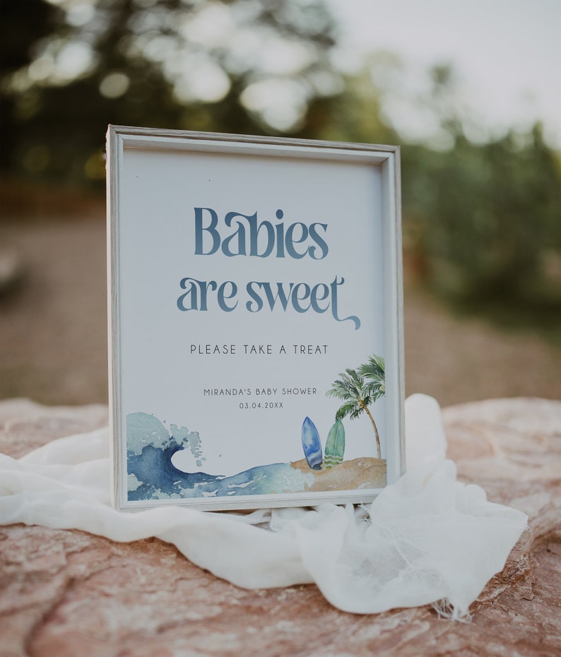 May include: A white framed sign with the text "Babies are sweet" in blue script. The sign also includes a watercolor illustration of a wave, palm trees, and surfboards. The text "Please take a treat" is below the main text, and the text "Miranda's Baby Shower 03.04.20XX" is below that.