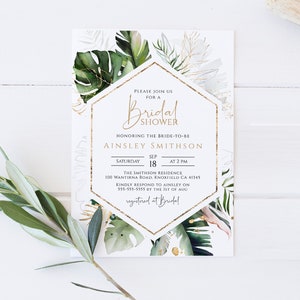 Puede incluir: Una invitaci&oacute;n de ducha nupcial blanca con detalles dorados e ilustraciones de hojas tropicales. La invitaci&oacute;n incluye el texto "Por favor, &uacute;nase a nosotros para una ducha nupcial" y el nombre de la novia, "Ainsley Smithson". Tambi&eacute;n se incluyen la fecha, la hora y el lugar de la ducha.
