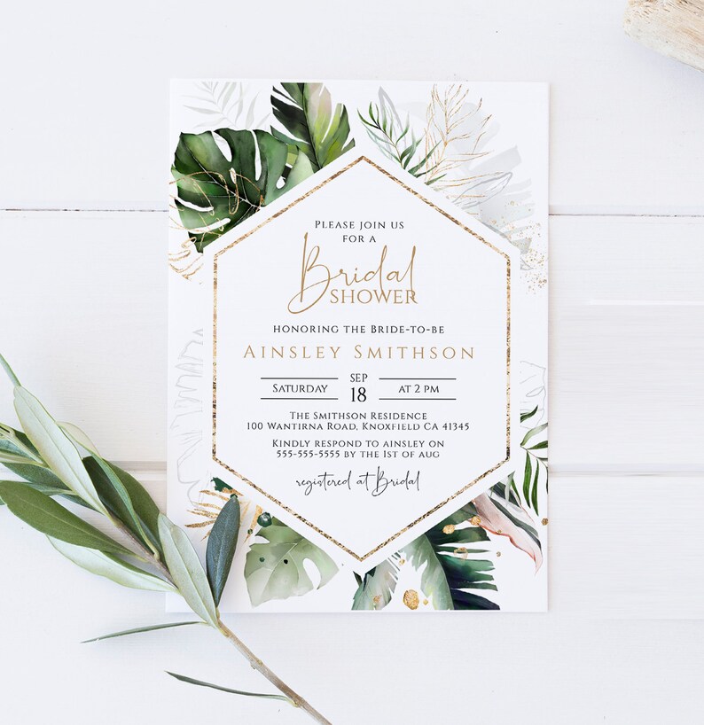 Puede incluir: Una invitaci&oacute;n de ducha nupcial blanca con detalles dorados e ilustraciones de hojas tropicales. La invitaci&oacute;n incluye el texto "Por favor, &uacute;nase a nosotros para una ducha nupcial" y el nombre de la novia, "Ainsley Smithson". Tambi&eacute;n se incluyen la fecha, la hora y el lugar de la ducha.