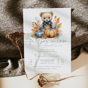 May include: A baby shower invitation featuring a watercolour illustration of a teddy bear wearing a blue bow tie, surrounded by autumn leaves, pumpkins and blue flowers. The text reads "falling in love with baby Smithson".
