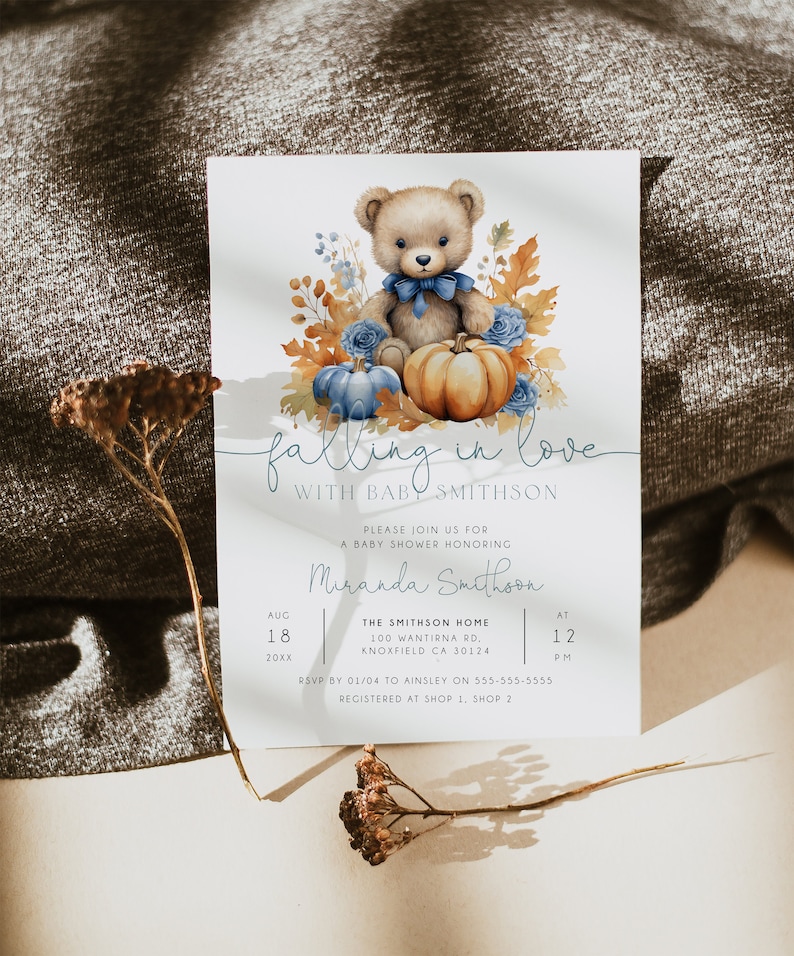 May include: A baby shower invitation featuring a watercolour illustration of a teddy bear wearing a blue bow tie, surrounded by autumn leaves, pumpkins and blue flowers. The text reads "falling in love with baby Smithson".