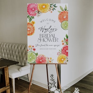Puede incluir: Un cartel de bienvenida blanco con una ilustraci&oacute;n de acuarela de c&iacute;tricos y flores. El texto en el cartel dice "Bienvenido al Shower Nupcial de Hayley. &iexcl;Ha encontrado a su alma gemela! &iexcl;Estamos encantados de que est&eacute;s aqu&iacute;!"