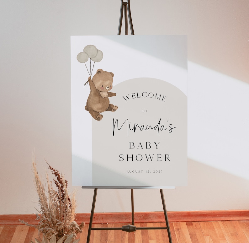 Puede incluir: Bienvenido a la fiesta de bienvenida al beb&eacute; de Miranda con un oso marr&oacute;n sosteniendo globos. El cartel est&aacute; sobre un fondo blanco con un c&iacute;rculo gris claro alrededor del texto. La fecha de la fiesta es el 12 de agosto de 2023.