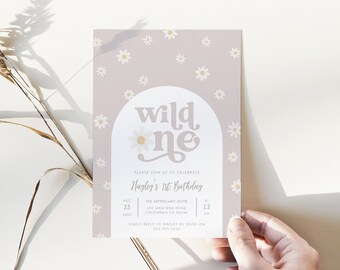 May include: A floral-themed invitation card with the text "wild one" in a retro font. The card is light purple with daisy illustrations and details for a first birthday celebration, including the date, time, and location.