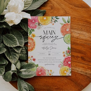 K&ouml;nnte beinhalten: Eine wei&szlig;e Karte mit einem Design aus Zitrusfr&uuml;chten und dem Text "She found her Main Squeeze" und "Haley Jones". Die Karte ist eine Einladung zu einer Bridal Shower mit Details zur Veranstaltung, einschlie&szlig;lich Datum, Uhrzeit und Ort.