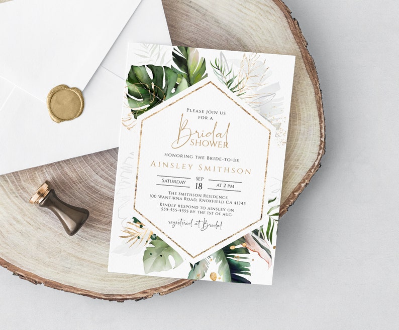 Puede incluir: Una invitaci&oacute;n blanca con detalles dorados e ilustraciones de hojas tropicales. El texto dice "Por favor, &uacute;nase a nosotros para un Shower de Novia en honor a la futura novia Ainsley Smithson. S&aacute;bado, 18 de septiembre a las 2:00 PM. The Smithson Residence, 100 Wantrina Road, Knoxfield CA 41345. Por favor, responda a Ainsley al 555-555-5555 antes del 1 de agosto. Registrado en Bridal."