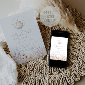 May include: A blue and white teacup with a floral design is featured on a light blue invitation with the text "Time for Tea with the Bride-to-be Samantha Jones" and details for a bridal shower. The invitation is printed on a white background with a floral design. The invitation is displayed on a woven straw mat with a smartphone showing a similar invitation.