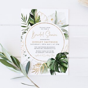 Op de afbeelding: Een witte kaart met een gouden cirkelrand en groene tropische bladeren. De tekst luidt "U bent van harte welkom op een Bridal Shower ter ere van Ainsley Smithson Zaterdag 18 augustus | om 14:00 uur The Smithson Residence 100 Red Rd | Knoxfield CA Graag uw antwoord v&oacute;&oacute;r 01/08 aan Ainsley | 555-555-555 Geregistreerd bij Wedding Shop"